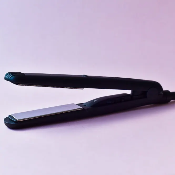 Pembe zemin üzerinde açık, siyah saç düzleştirici.